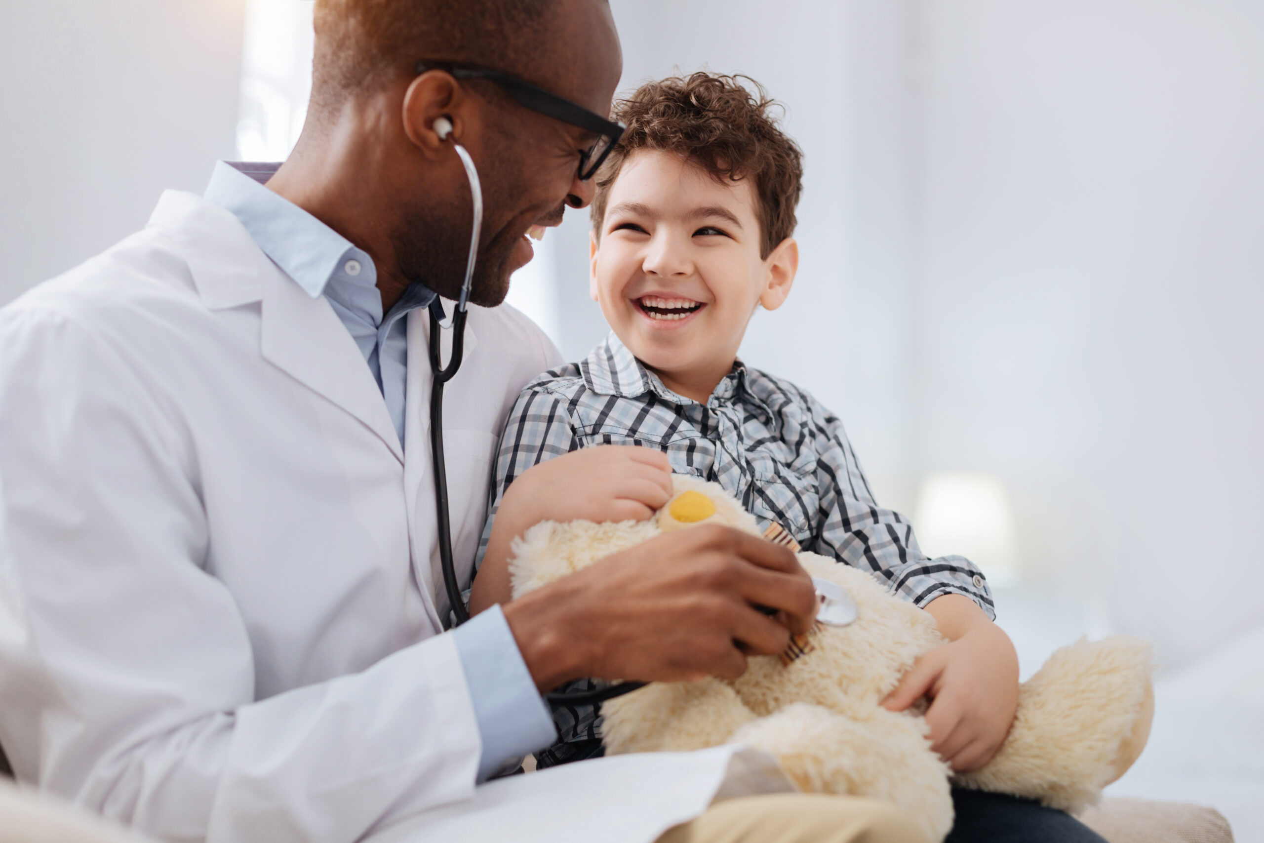 doctor playfully diagnosing plush bear making a child laugh